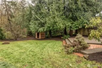 Side yard with additional usable space and wooded backdrop.