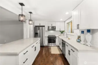 Updated kitchen with large island, white cabinets, granite countertops, and stainless steel appliances.