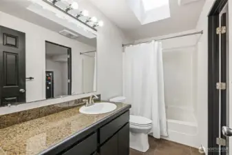 Bright, spacious full bath with skylight—door to the right opens to the primary bedroom.