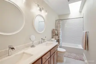 Upstairs hallway bathroom with gorgeous tile work, quartzite countertops, quality cabinetry and skylight.