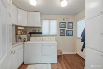 Nice laundry room with cabinets, new flooring and a door leading out to the side of the house.