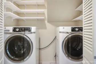 The laundry area offers plenty of shelving. Washer and dryer remain with the home.