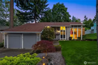 A wide driveway leads to a spacious two-car garage, while thoughtfully placed shrubs and seasonal blooms add warmth and character. The home's modern yet welcoming facade is bathed in natural light, setting the tone for the comfort and style that await inside....