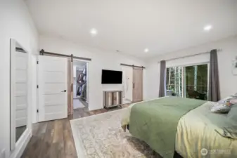Barn Doors for both the closet and the bath .  Another view of the Primary Bedroom shows the lighting, deck access, and luxury flooring!