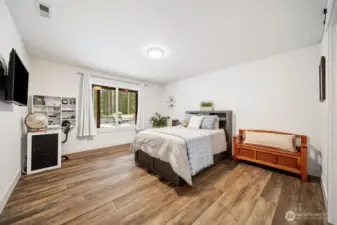 We are now in the lower level... Bedroom 3 with a walk-in closet, luxury vinyl flooring, and a big window overlooking the backyard.
