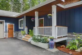 Inviting covered porch with a swing (stays with home)  Catch the sunset colors peeking thru the woods!  The front porch has a Ring camera and owners are leaving. The man door leads to the garage and it is spotless!