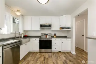 Spacious, updated kitchen with stainless steel appliances, farmhouse-style sink, and newly painted cabinets.
