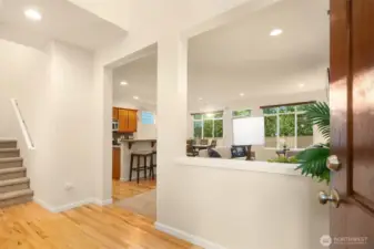 Two story entrance with hardwood flooring and peek-a-boo view into the great room/kitchen area.