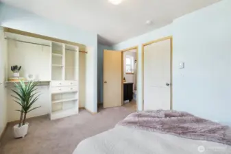 Spacious primary bedroom with shelving unit and attached bathroom.