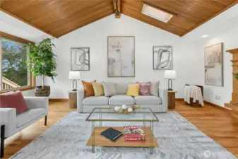 Fireplace to right, sliding glass doors to deck to left, dining behind.