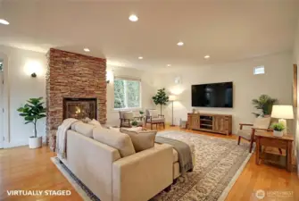 Living room w/ a stacked stone gas fireplace.