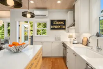 Stunning quartz countertops, custom deep storage drawers,  and solid wood floors in the kitchen overlooking the preserved woodland and Thornton Creek.