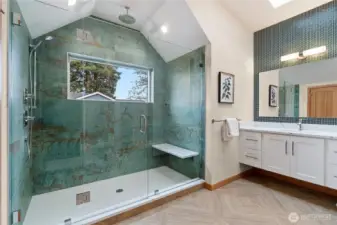 Incredible ensuite bath with custom tile, vaulted shower ceilings, and window showcasing the surrounding trees.