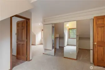 Primary bedroom has a dressing area with closets and space for dresser.  Bed area is separated by design.