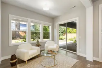 Just off the open-concept kitchen, this light-filled sitting room offers a cozy spot for morning coffee or casual conversation. Large windows and sliding glass doors frame the lush backyard, blending indoor comfort with outdoor serenity.