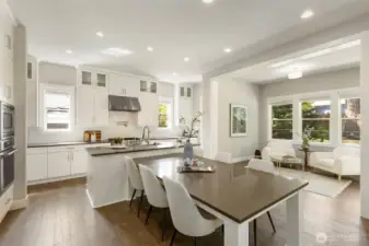 Anchoring the home with style and function, this modern kitchen boasts an oversized island with seating, quartz countertops, and a professional-grade range with a statement hood. Bathed in natural light and open to a charming sitting area, it’s perfectly designed for both daily living and elegant entertaining.