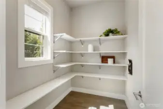 This spacious walk-in pantry offers generous open shelving and natural light, making it as functional as it is inviting. Perfectly positioned off the kitchen, it keeps everyday essentials organized and easily accessible.