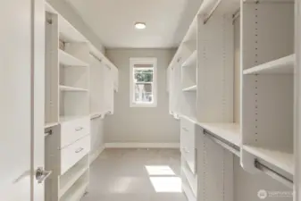 The expansive walk-in closet in the primary suite is outfitted with custom built-ins, ample hanging space, and natural light from a central window. Designed for both function and elegance, it offers a beautifully organized start and finish to each day.