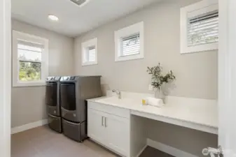 This upstairs laundry room is bright, spacious, and thoughtfully designed with a deep utility sink, extended folding counter, and built-in cabinetry for storage. Please note: the washer and dryer are not included in the sale.
