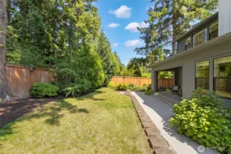 This alternate view of the backyard showcases the seamless blend of manicured lawn, mature privacy trees, and a spacious patio perfect for outdoor dining or lounging. With lush landscaping and room to roam, it’s an ideal setting for peaceful mornings, playful afternoons, or evening gatherings under the stars.