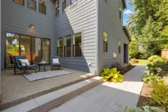This inviting side yard features a charming patio just off the dining room—an ideal spot for quiet morning coffee or evening conversation. Surrounded by lush landscaping and easy-care pathways, it’s a private extension of the home’s indoor-outdoor lifestyle.