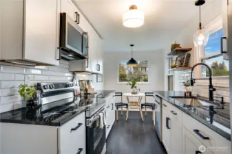 Stunning brand-new kitchen featuring sleek white shaker cabinets, black granite countertops, subway tile backsplash, stainless appliances, matte-black pull-down faucet, and modern pendant lighting. Dark luxury tile plank flooring, bright window over the sink, and a cozy built-in eating nook make this the perfect blend of style and function. Completely remodeled and ready for your first meal!