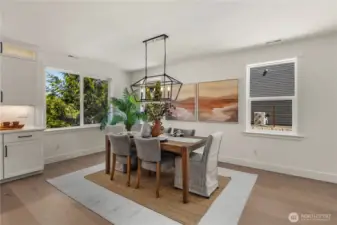 Dining Room: Bright and inviting dining space framed by oversized windows and a modern chandelier, creating a perfect backdrop for everyday meals or entertaining. Its open flow connects seamlessly to the kitchen for convenience and style. Staged photos are of the model home of the same floorplan within the Foxmoore community and are for visualization purposes only. Colors, finishes, and layout can and will vary.