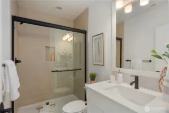 Main Level Bath: Full bathroom with modern fixtures, tiled shower, and quartz-topped vanity, providing convenience for guests or a main-level bedroom. Staged photos are of the model home of the same floorplan within the Foxmoore community and are for visualization purposes only. Colors, finishes, and layout can and will vary.