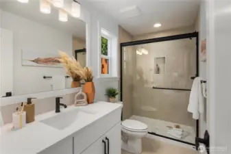 Lower Level Ensuite Bath: Thoughtfully designed en-suite bath offers a quartz-topped vanity, framed mirror, and a walk-in shower with full-height tile surround. Conveniently located off the lower-level suite, it ensures both style and privacy for guests. Staged photos are of the model home of the same floorplan within the Foxmoore community and are for visualization purposes only. Colors, finishes, and layout can and will vary.