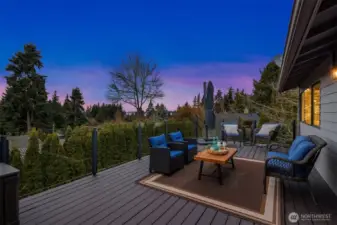 Sunset views from your private sanctuary. This expansive composite deck offers glass railings for an unobstructed view of the lush Pacific Northwest horizon.