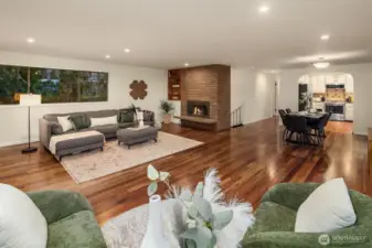 Warmth meets modern design. The spacious open-concept living room features rich hardwood floors and a signature brick fireplace that serves as the heart of the home.