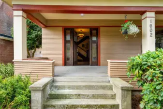 A large front porch with a deck swing leads to a Dutch front door.