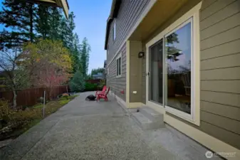 Fully fenced-in backyard with a large patio, garden space and a shed on the other side for additional storage.