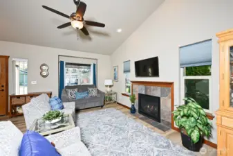 Living room with LVP flooring, vaulted ceilings, and a gas fireplace.