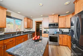 Expansive Chef's kitchen with beautiful wood cabinets, granite countertops, newer stainless steel appliances, an island for more prep space and a butler's pantry.
