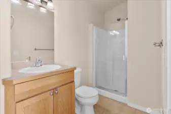 Ensuite bathroom with single-sink vanity, wall mirror, toilet, and glass-enclosed shower.