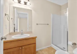 Private bathroom with single-sink vanity, wall mirror, toilet, and glass-enclosed shower.