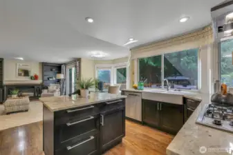 The updated kitchen is both functional and elegant, featuring slab granite counters, a farmhouse-style sink, and generous natural light from oversized windows that overlook the private backyard.
