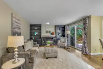The adjacent family room is anchored by an electric fireplace with custom built-ins, offering a welcoming setting for gatherings and quiet nights in. Sliding glass doors provide direct access to the deck.