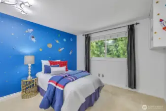 One of the secondary bedrooms enjoys a large window with backyard views and a playful wall design, perfect for customizing to your lifestyle needs—whether for rest, study, or creative play.