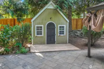 A charming playhouse adds a whimsical touch and additional functionality to the backyard—a delightful feature for imaginative play or garden storage.