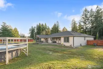 The yard is spacious and private inside the wooden fence, and behind the photographer are the RV spaces. The pool is surrounded by a solid deck and the big covered deck keeps you out of the NW elements.