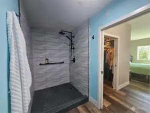 Primary en suite features custom tile shower, LVP flooring, walk-in closet