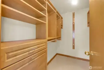 Primary suite closet with custom built-in shelving, drawers and hamper.