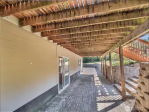 Large paved area below deck with entrance to daylight basement.