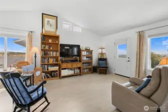 Living room with vaulted ceilings and TONS of natural light, also beautiful laminate flooring.