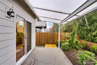 Covered patio overlooking landscaped yard.  Owner installed this very cool covered solid awning that lets so much light into the house.  The patio extends the entire back side of the house (upgrade when built).