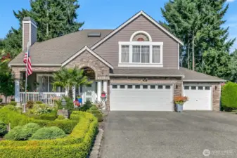 Striking stone-accented façade with arched entry and welcoming covered porch.
