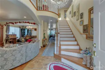 Inviting entryway with soaring ceilings, elegant chandelier, and sweeping staircase.