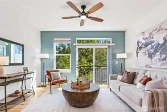 Bask in south-facing sunshine and breezes from the Juliet balcony, with views of trees and the patio below. A smoky blue accent wall and modern ceiling fan set the mood, while the sleek wood-and-concrete staircase anchors the space with architectural flair—making this living room as stylish as it is inviting.